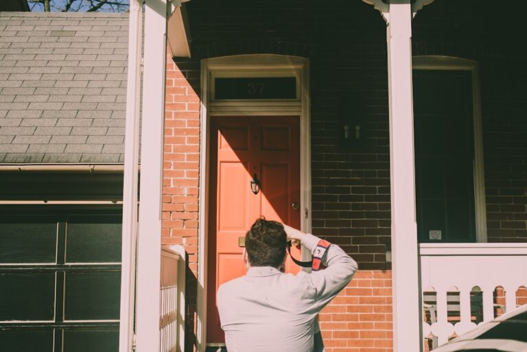 A person closely inspecting window frames and walls for damage inside a single-family house.