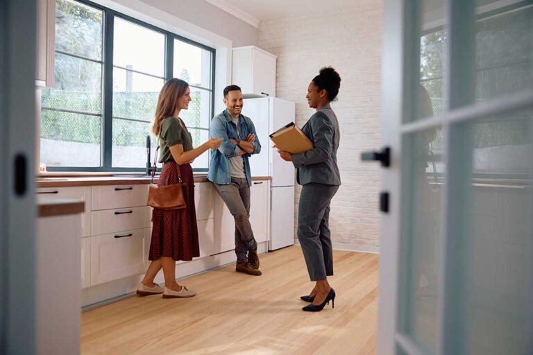 A couple reviews a home purchase offer and negotiations paperwork at their kitchen table.